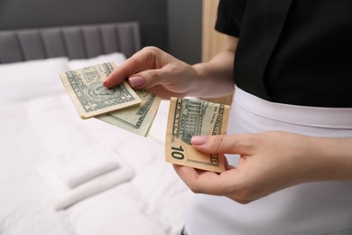 Photo of Chambermaid with tips near bed in hotel room, closeup. Gratuity for work