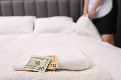 Photo of Chambermaid working in hotel room, focus on tips and towels on bed