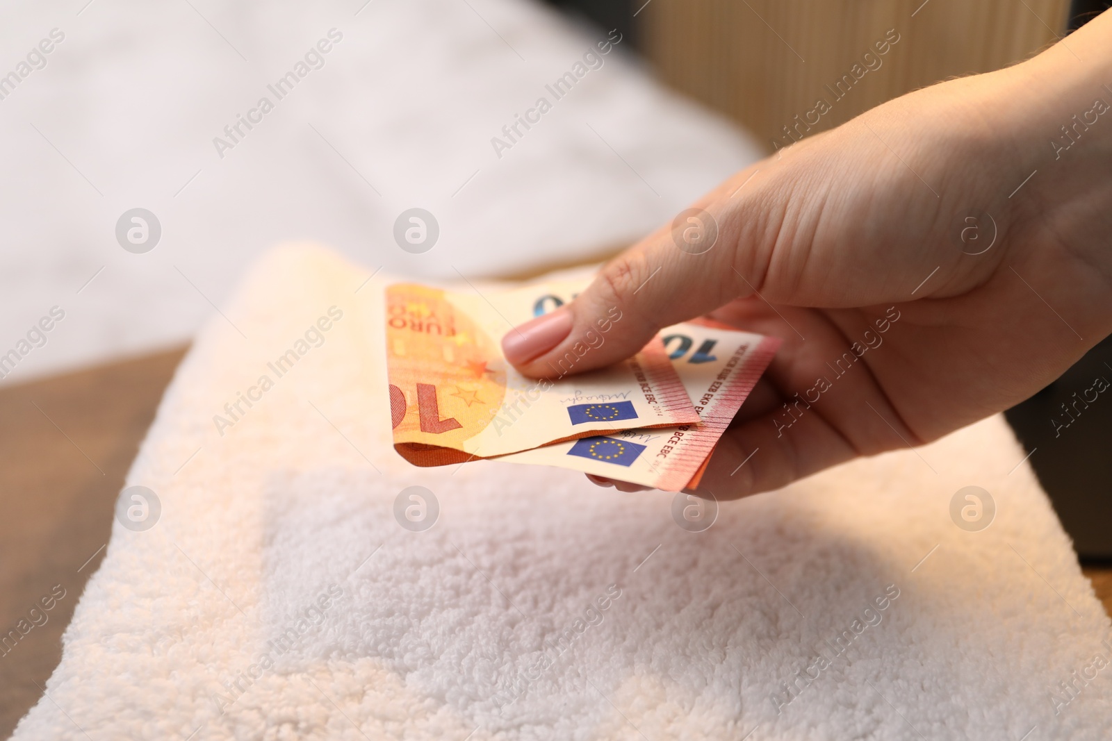 Woman putting tips onto towel in hotel, closeup Photo of Woman putting tips onto towel in hotel, closeup