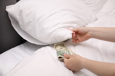 Photo of Woman putting tips under pillow on bed in hotel, closeup. Gratuity for work