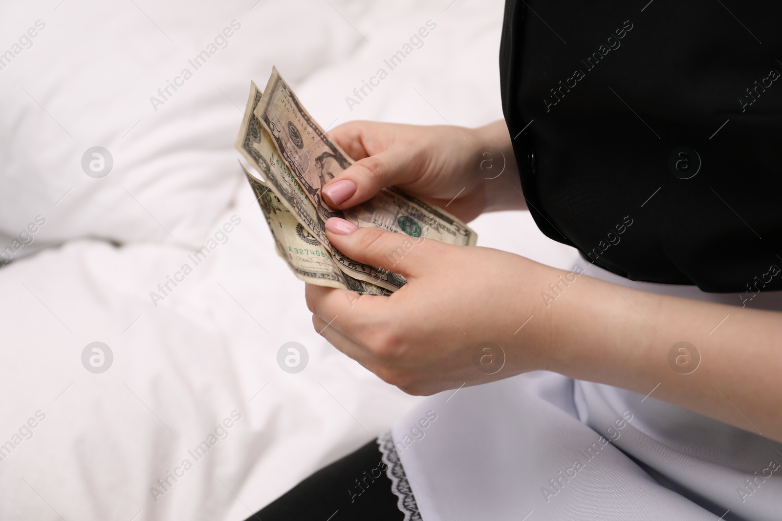 Photo of Chambermaid with tips on bed in hotel room, closeup. Gratuity for work