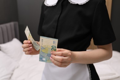 Photo of Chambermaid with tips near bed in hotel room, closeup. Gratuity for work