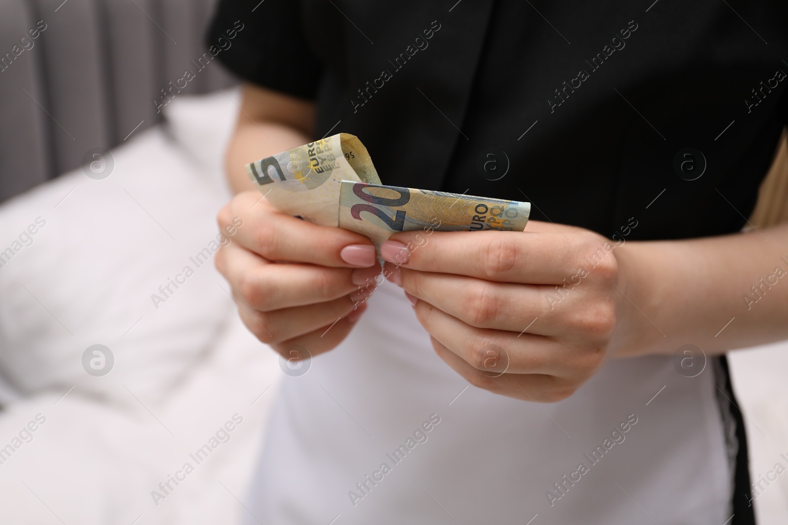 Photo of Chambermaid with tips near bed in hotel room, closeup. Gratuity for work