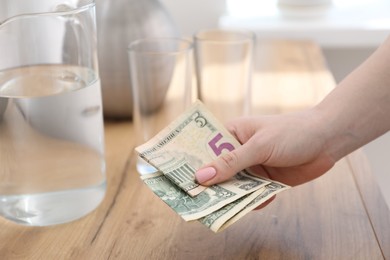 Photo of Woman putting tips onto wooden table, closeup