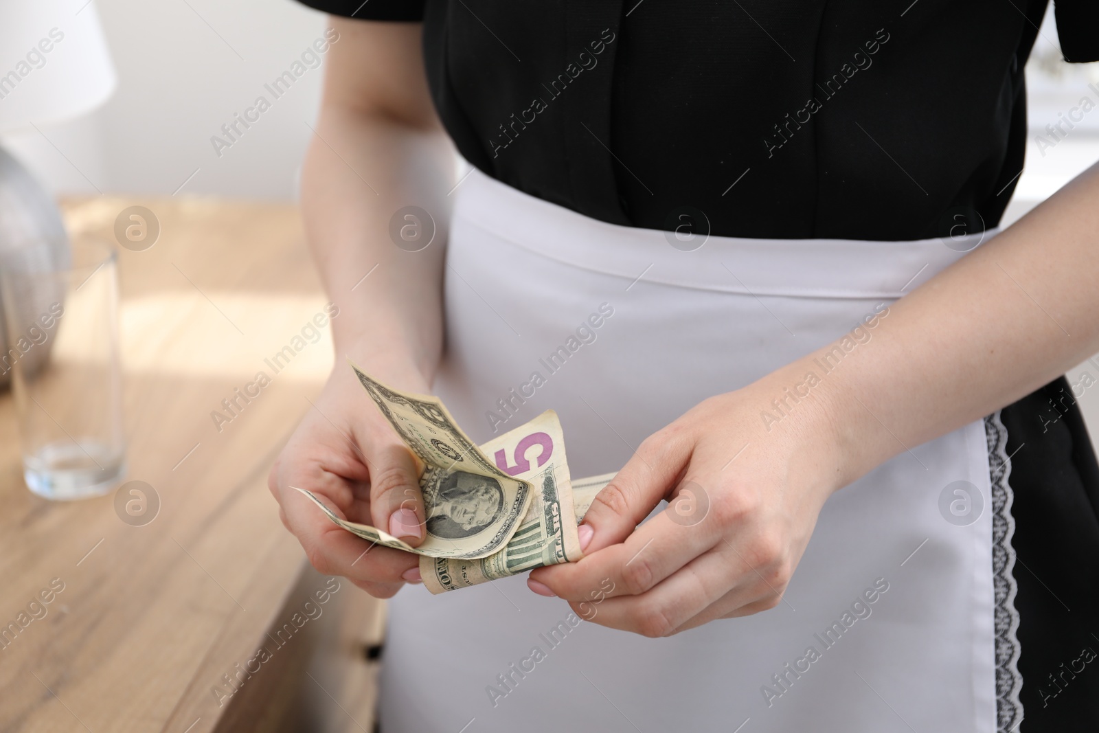 Photo of Chambermaid with tips in hotel room, closeup. Gratuity for work