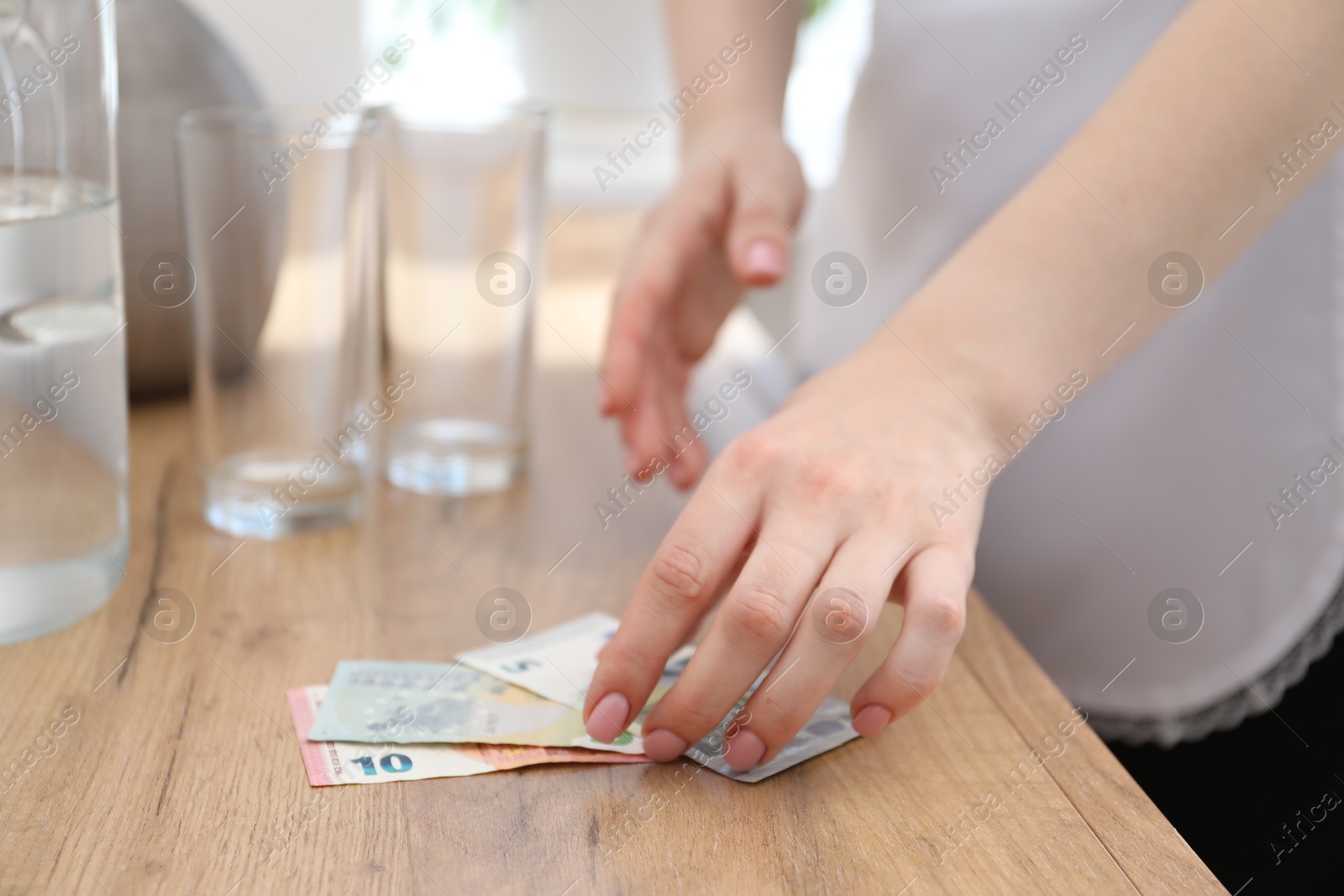 Chambermaid taking tips from wooden nightstand in hotel room, closeup. Gratuity for work Photo of Chambermaid taking tips from wooden nightstand in hotel room, closeup. Gratuity for work