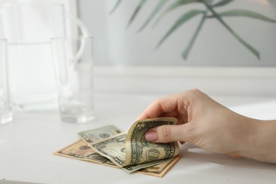 Photo of Woman taking tips from white wooden counter in hotel room, closeup. Gratuity for work