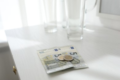Photo of Tips on white wooden nightstand in hotel room, closeup. Gratuity for work