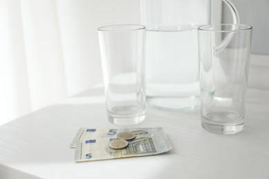 Photo of Tips, glasses and jug of water on white counter, closeup