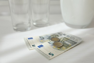 Photo of Tips on white wooden table, closeup. Gratuity for work