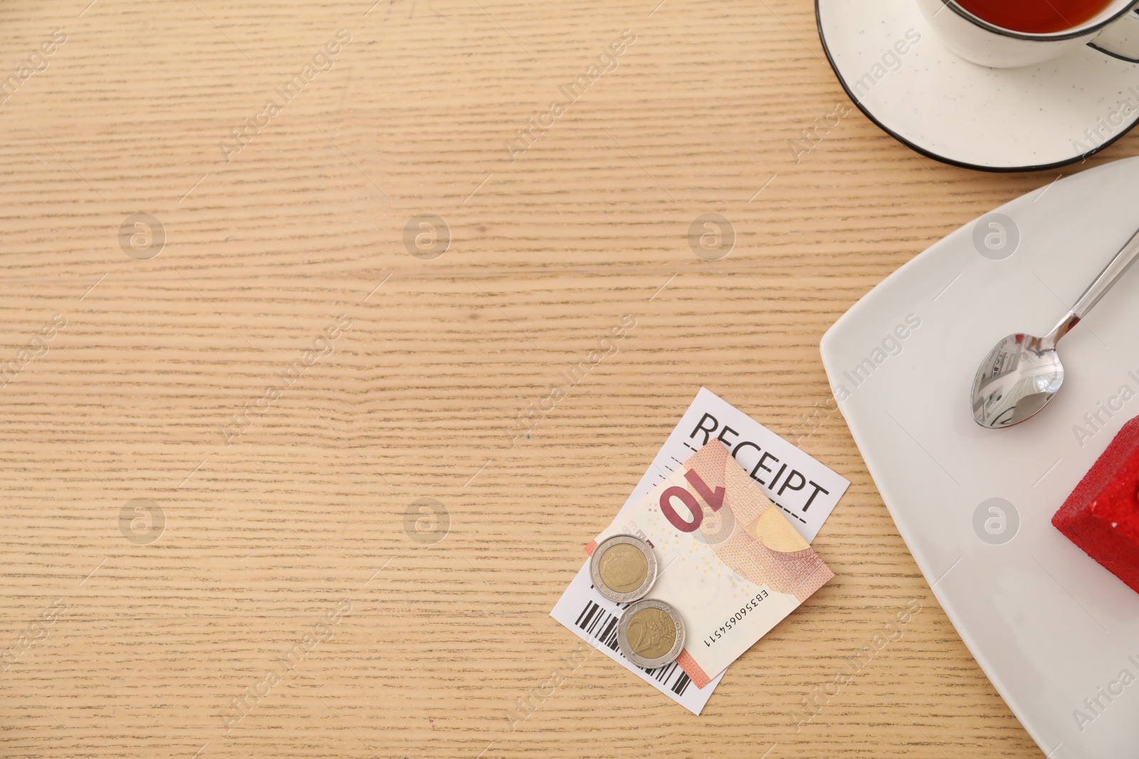 Photo of Tips, receipt and dishware on wooden table, flat lay. Space for text