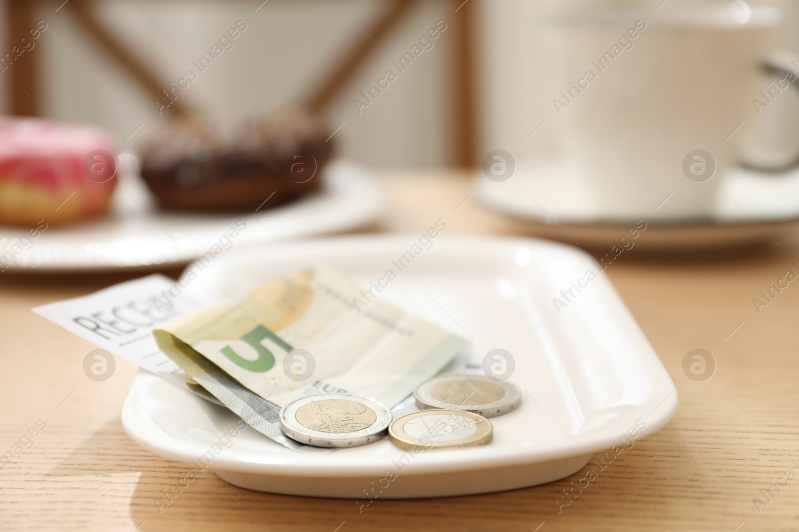 Photo of Tips and receipt on wooden table in restaurant, closeup. Gratuity for work