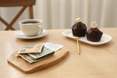 Photo of Tips, receipt and order on wooden table in restaurant, closeup. Gratuity for work