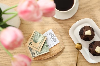 Photo of Tips, receipt and order on wooden table, flat lay