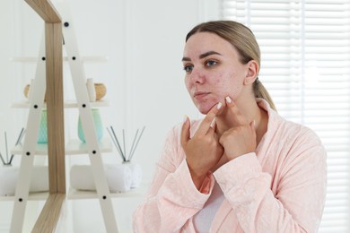 Photo of Woman popping pimple near mirror in bathroom. Acne problem
