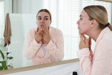 Photo of Woman popping pimple near mirror in bathroom. Acne problem
