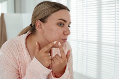 Photo of Woman popping pimple in bathroom, space for text. Acne problem