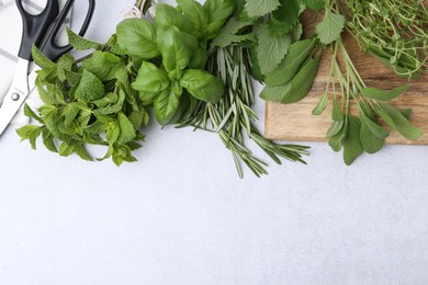 Photo of Different fresh green herbs and scissors on light table, flat lay. Space for text
