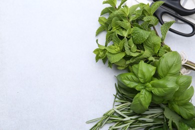 Photo of Different fresh green herbs and scissors on light table, flat lay. Space for text