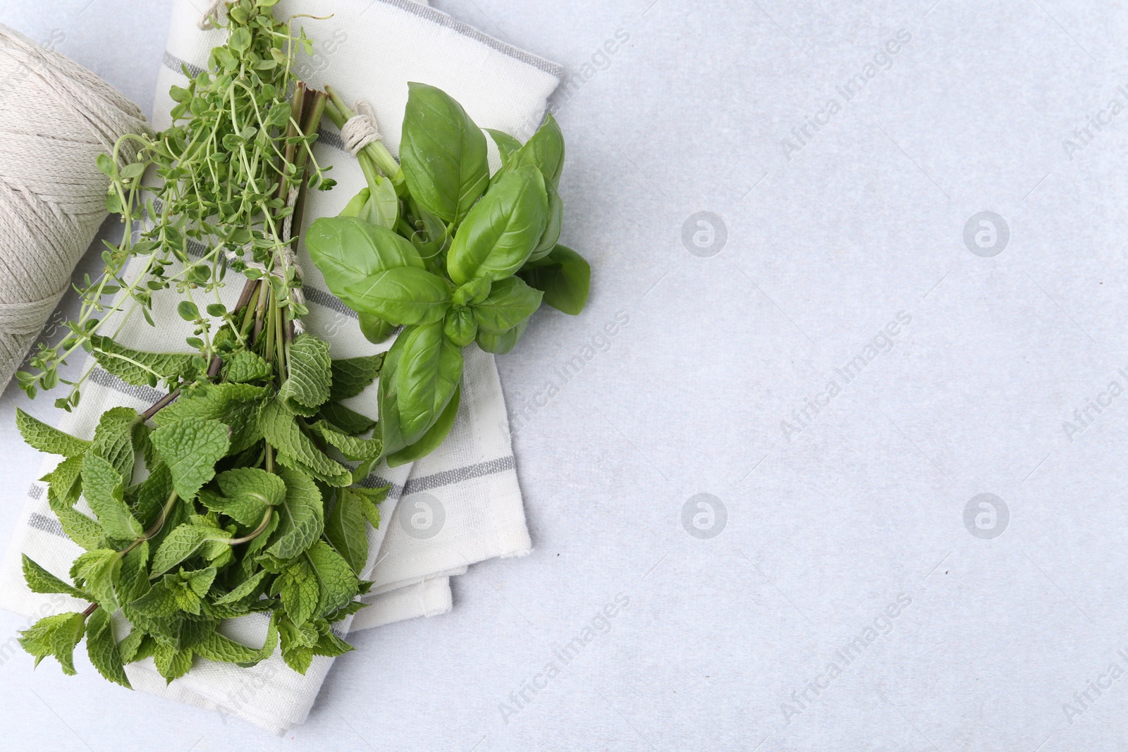 Photo of Different fresh green herbs and twine on light table, flat lay. Space for text