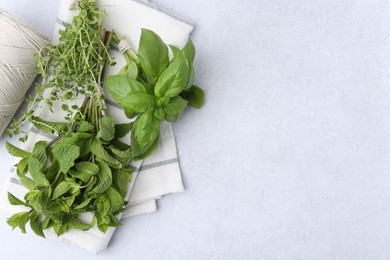 Photo of Different fresh green herbs and twine on light table, flat lay. Space for text