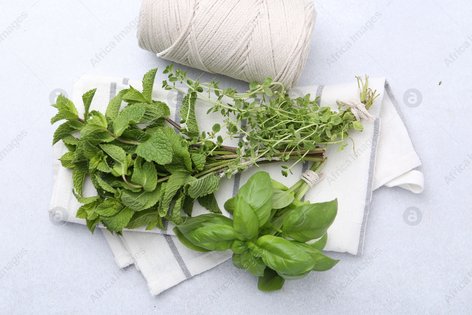 Photo of Different fresh green herbs and twine on light table, flat lay