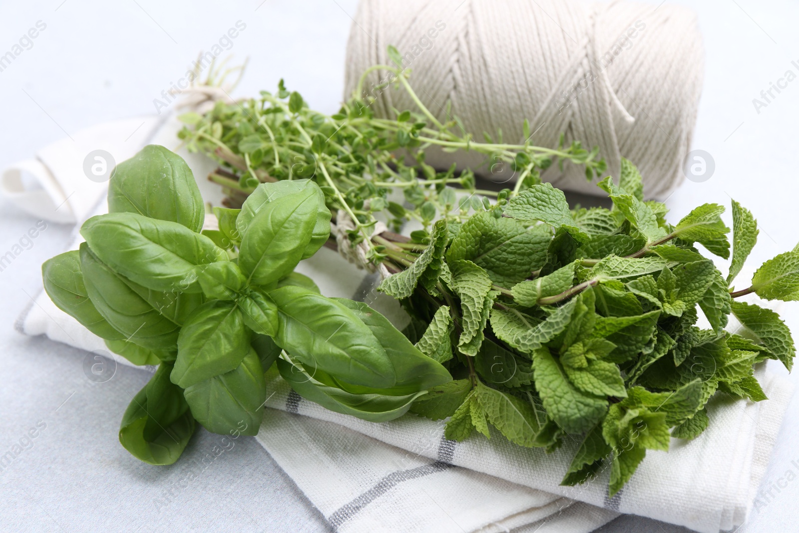 Photo of Different fresh green herbs and twine on light table, closeup