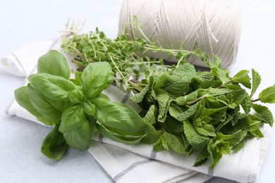 Photo of Different fresh green herbs and twine on light table, closeup