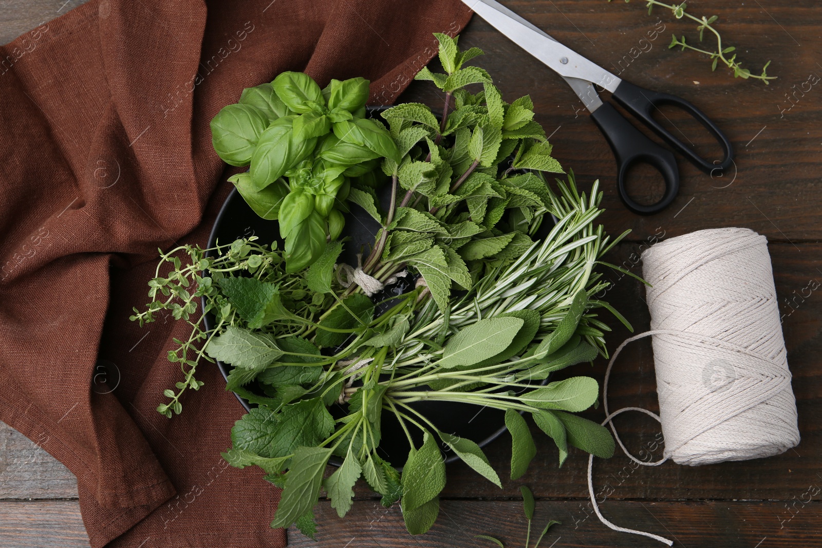 Different fresh green herbs, scissors and twine on wooden table, flat lay Photo of Different fresh green herbs, scissors and twine on wooden table, flat lay