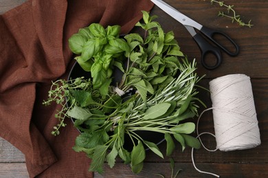 Photo of Different fresh green herbs, scissors and twine on wooden table, flat lay