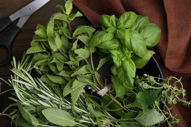 Photo of Different fresh green herbs in bowl and scissors on wooden table, flat lay