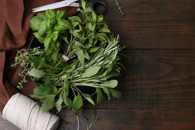 Photo of Different fresh green herbs in bowl, scissors and twine on wooden table, flat lay. Space for text
