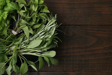Photo of Different fresh green herbs in bowl on wooden table, top view. Space for text