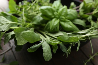 Photo of Different fresh green herbs in bowl on wooden table, closeup