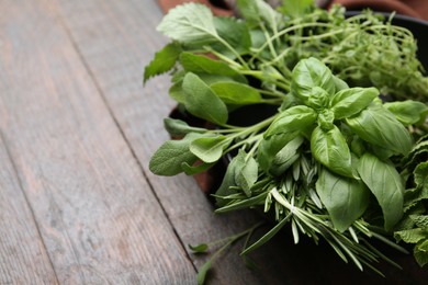 Photo of Different fresh green herbs in bowl on wooden table, closeup. Space for text