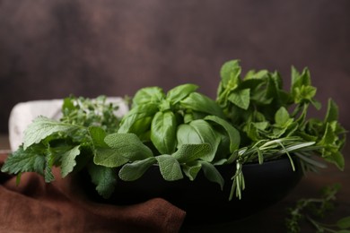 Photo of Different fresh green herbs in bowl on table, closeup