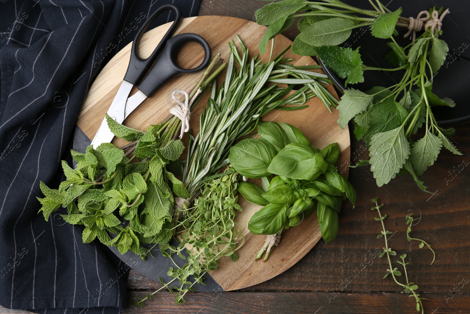 Different fresh green herbs and scissors on wooden table, flat lay Photo of Different fresh green herbs and scissors on wooden table, flat lay
