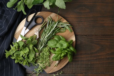 Photo of Different fresh green herbs and scissors on wooden table, flat lay. Space for text