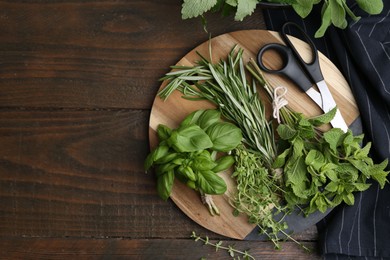 Photo of Different fresh green herbs and scissors on wooden table, flat lay. Space for text