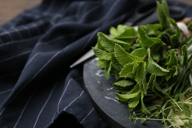 Photo of Different fresh green herbs and scissors on table, closeup. Space for text