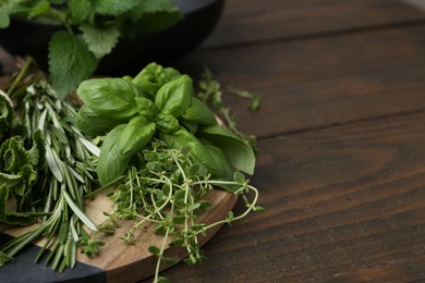Photo of Different fresh green herbs on wooden table, closeup. Space for text