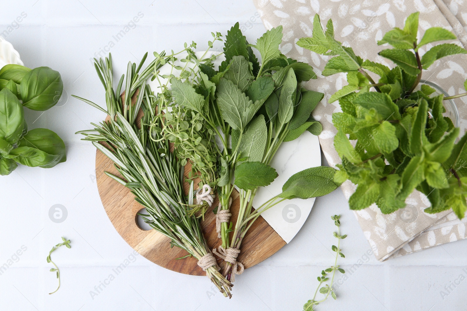 Photo of Different fresh green herbs on white tiled table, flat lay