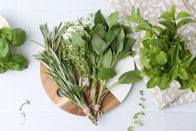 Photo of Different fresh green herbs on white tiled table, flat lay