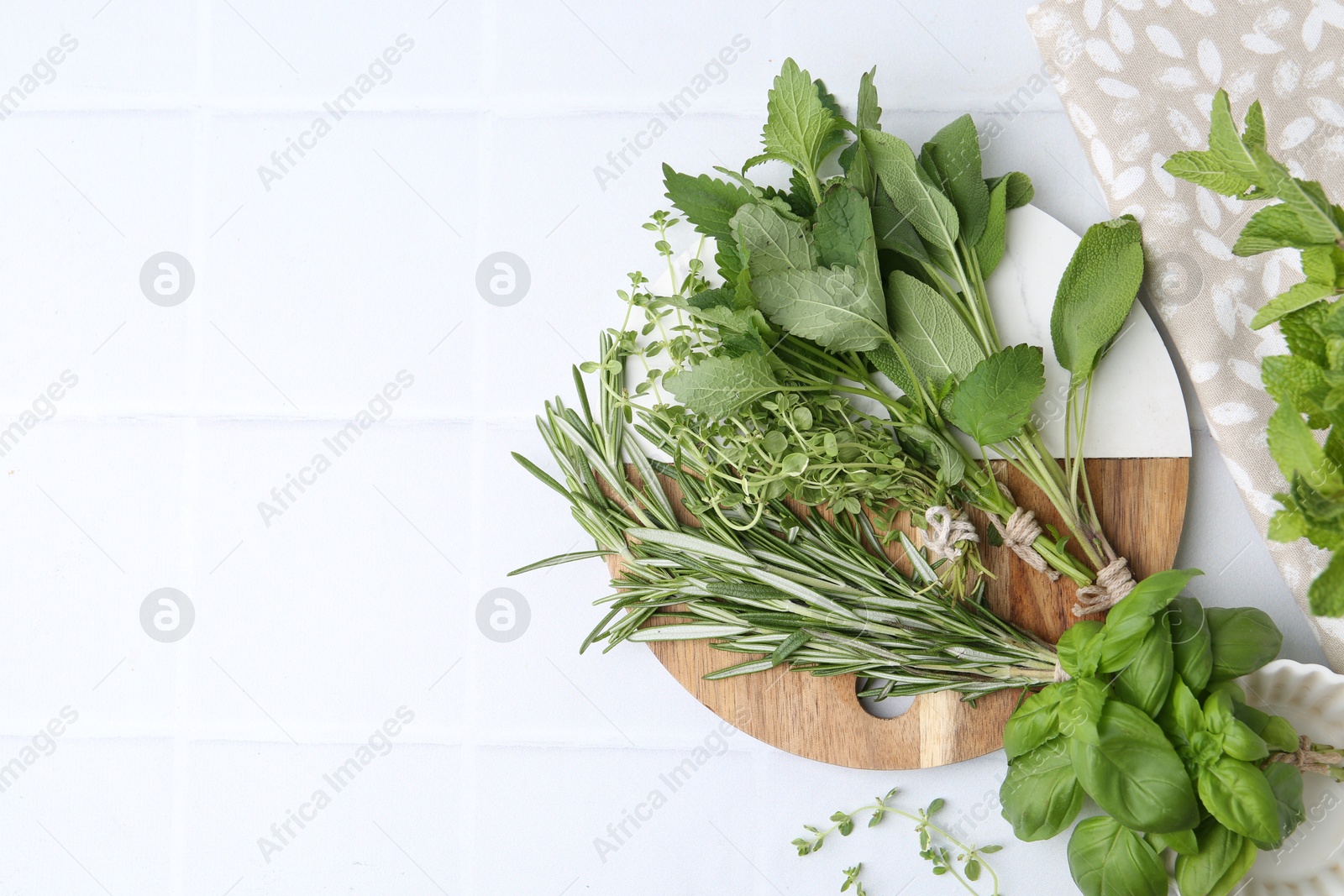 Photo of Different fresh green herbs on white tiled table, flat lay. Space for text