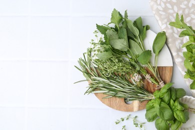 Photo of Different fresh green herbs on white tiled table, flat lay. Space for text