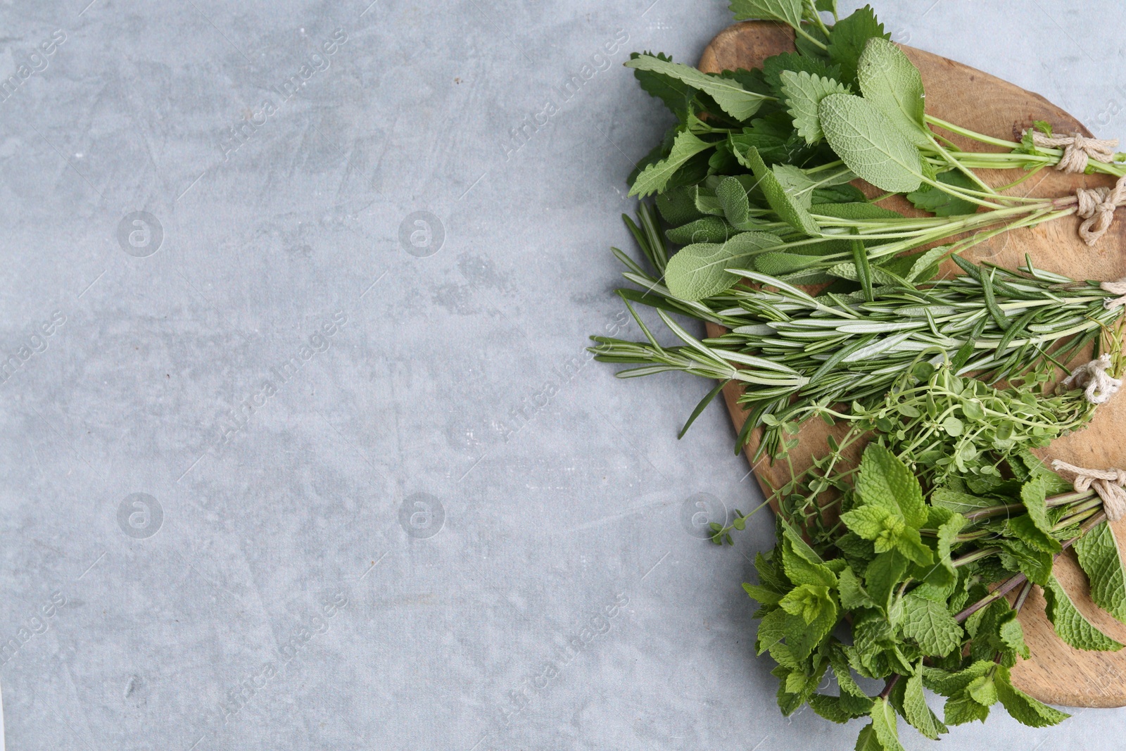 Photo of Different fresh green herbs on grey table, above view. Space for text