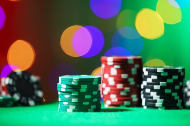 Photo of Casino chips on green table against blurred lights, closeup