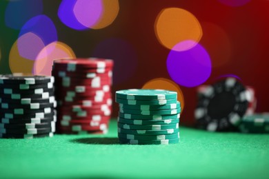 Photo of Casino chips on green table against blurred lights, closeup
