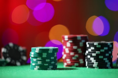 Photo of Casino chips on green table against blurred lights, closeup