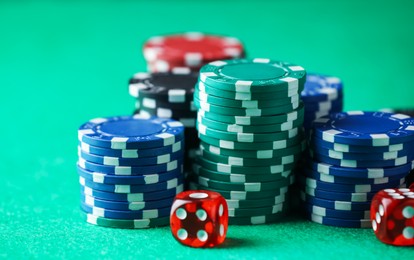 Photo of Casino chips and dice on green table, closeup